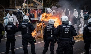 Riot police stand in front of burning barricades as activists stage a protest in Lützerath