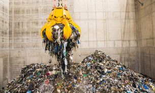 A mechanical claw picking up waste in a landfill